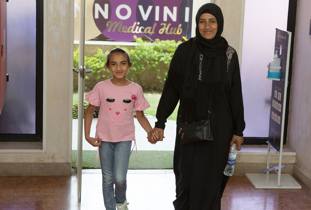 Azza and her mother Magda smiling and holding hands as they walk into Innovinity